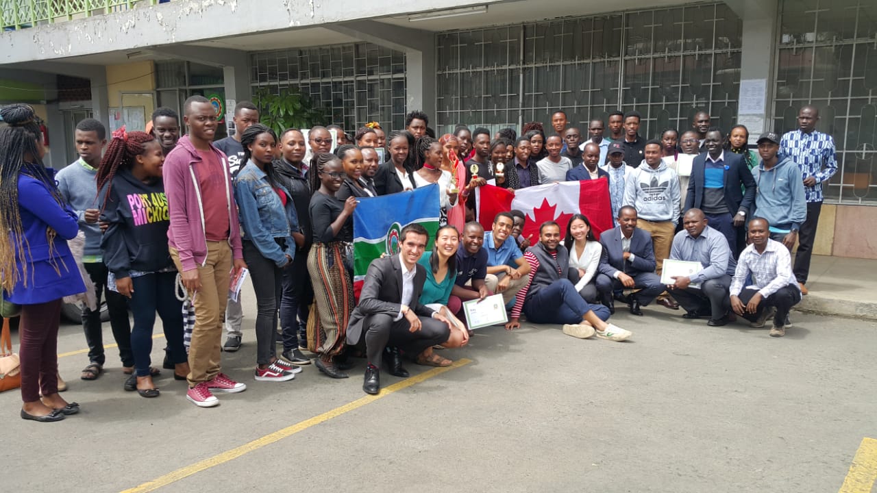 A large group of students posing together holding a Canadian flag