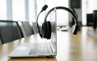 Laptop and headphones with mic on a board room table