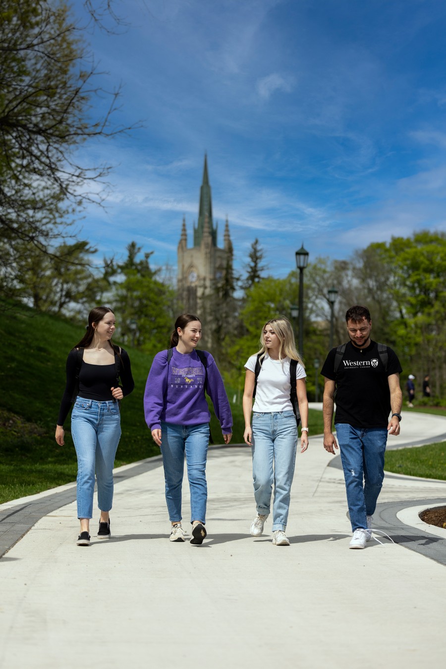 Western students walking along a path in front of the Western University tower