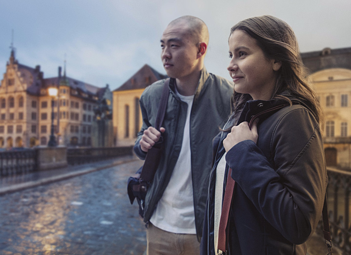 Two students standing on a bridge in a city